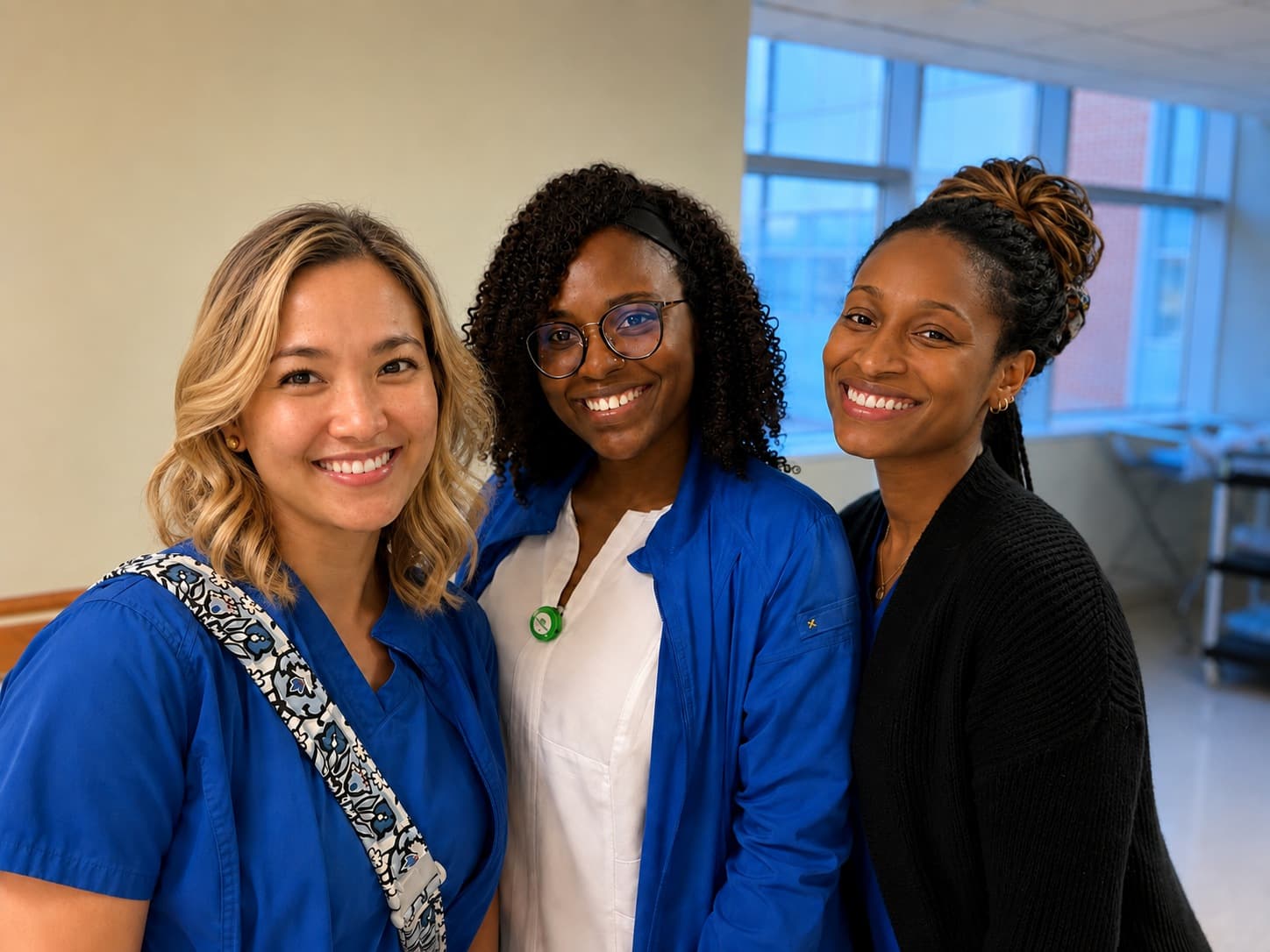 Four nurses in scrubs standing together in a bright corridor